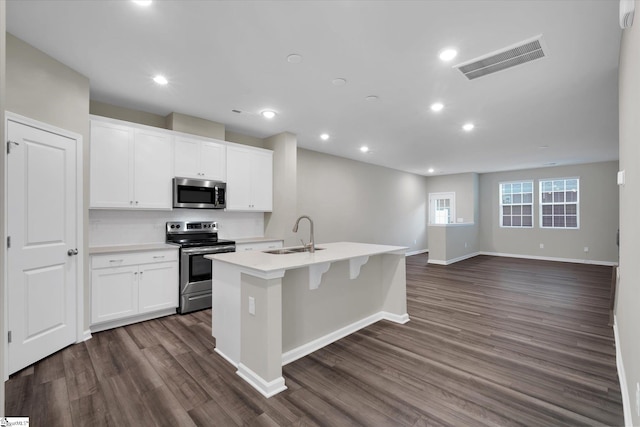 kitchen with white cabinetry, stainless steel appliances, sink, and a center island with sink