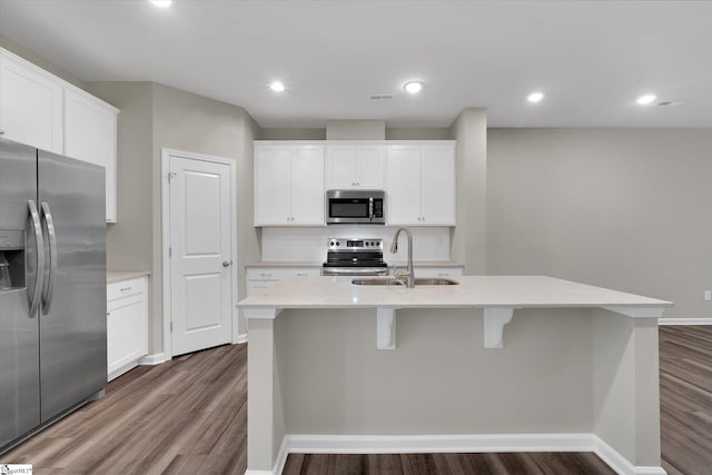 kitchen with white cabinetry, stainless steel appliances, sink, and an island with sink