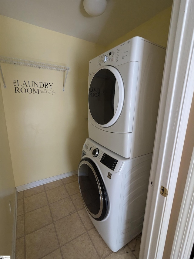 laundry area featuring stacked washer / drying machine and light tile patterned floors