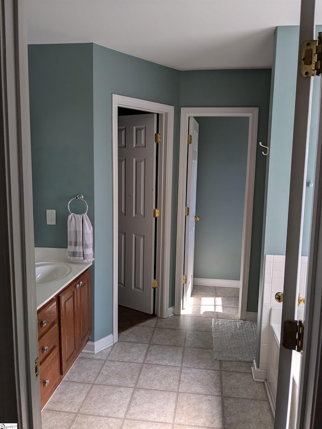 bathroom with a washtub, vanity, and tile patterned floors