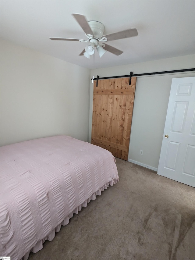 bedroom featuring a barn door, ceiling fan, and carpet flooring