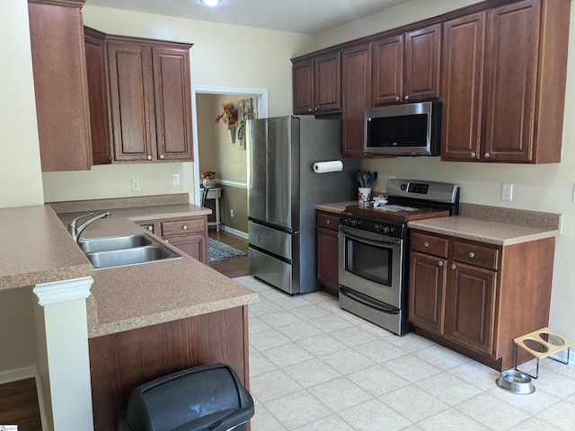 kitchen with dark brown cabinetry, kitchen peninsula, stainless steel appliances, and sink