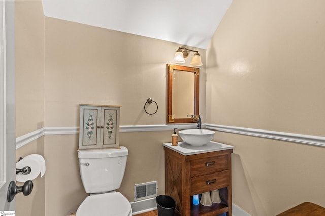 bathroom featuring vanity, toilet, and lofted ceiling