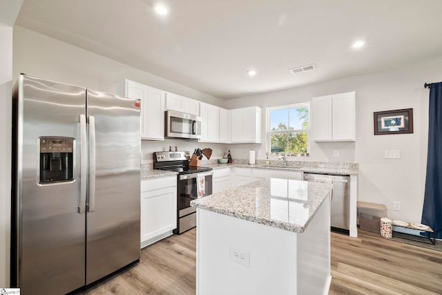 kitchen with white cabinets, sink, light hardwood / wood-style floors, appliances with stainless steel finishes, and a kitchen island