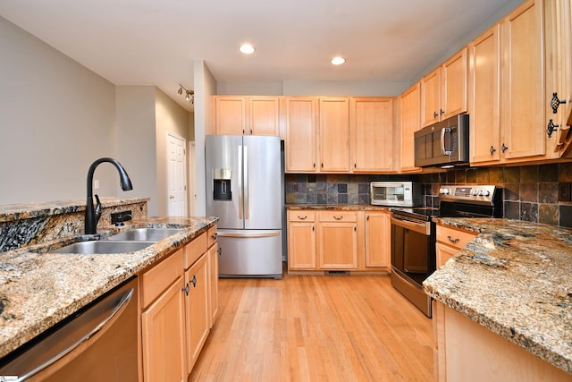 kitchen featuring appliances with stainless steel finishes, light brown cabinets, sink, and light hardwood / wood-style floors