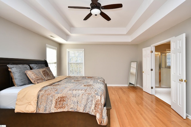 bedroom featuring ceiling fan, a tray ceiling, and hardwood / wood-style floors