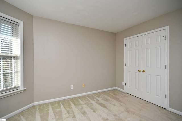 unfurnished bedroom with a closet and light carpet