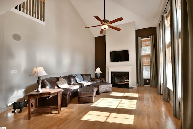 living room with ceiling fan, high vaulted ceiling, and light hardwood / wood-style flooring