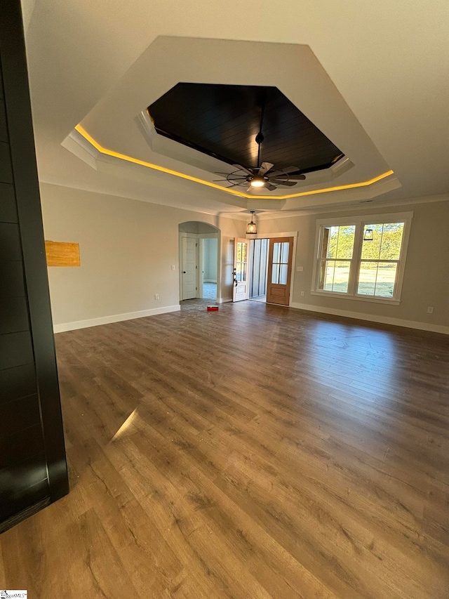 unfurnished living room featuring ceiling fan, a raised ceiling, and wood-type flooring