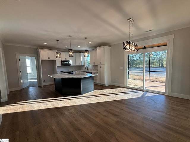 kitchen with a center island, hanging light fixtures, white cabinets, dark wood-type flooring, and ornamental molding