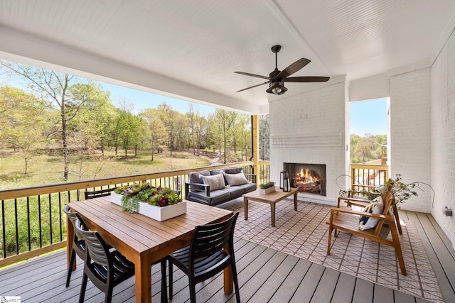 wooden deck with an outdoor living space with a fireplace and ceiling fan