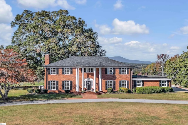 view of front of home with a front yard and a mountain view