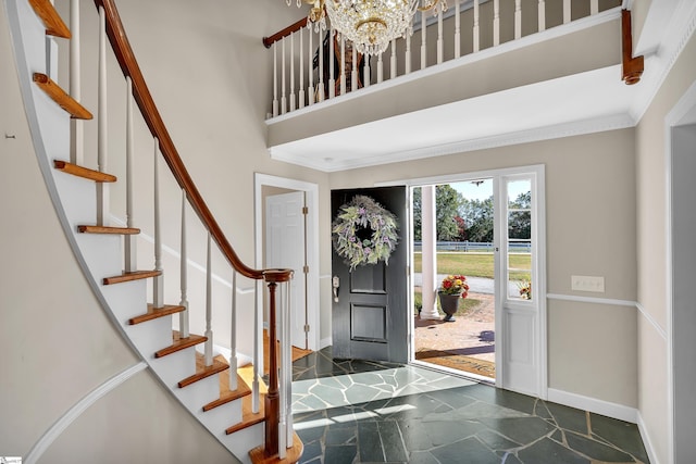 foyer featuring crown molding, a chandelier, and a high ceiling