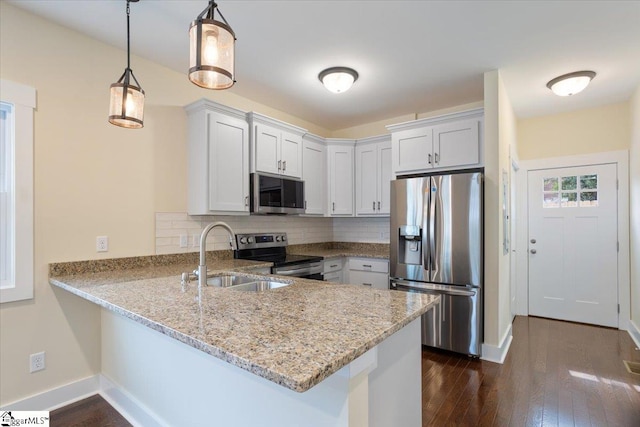 kitchen featuring appliances with stainless steel finishes, kitchen peninsula, white cabinetry, and pendant lighting