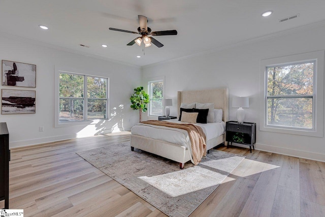 bedroom with ceiling fan, ornamental molding, multiple windows, and light wood-type flooring