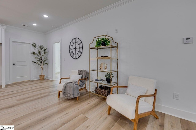 sitting room with crown molding and light wood-type flooring