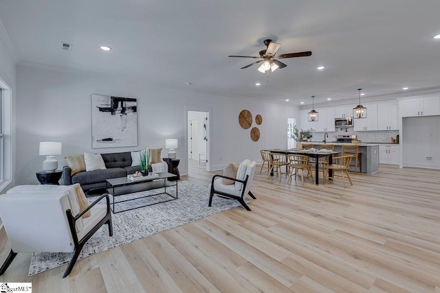 living room with sink, ceiling fan, ornamental molding, and light hardwood / wood-style flooring