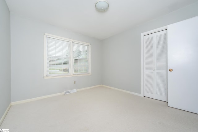 unfurnished bedroom with a closet and light colored carpet