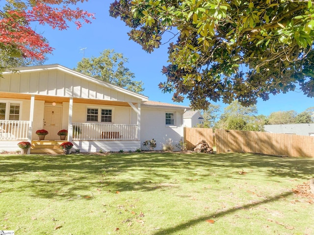 rear view of property featuring a yard and covered porch