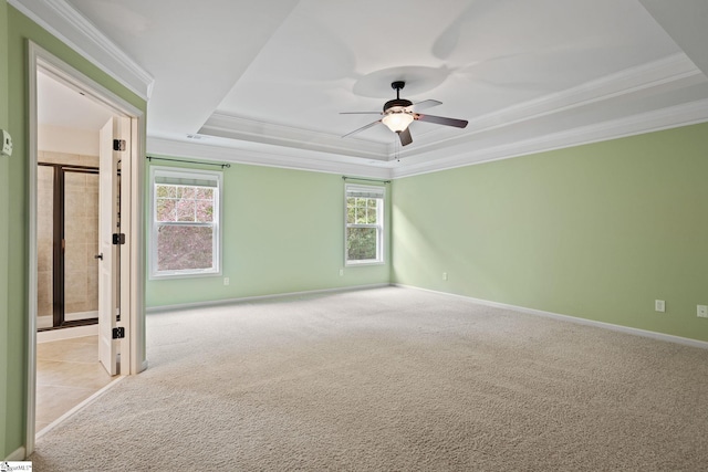 carpeted empty room with ceiling fan, crown molding, and a tray ceiling