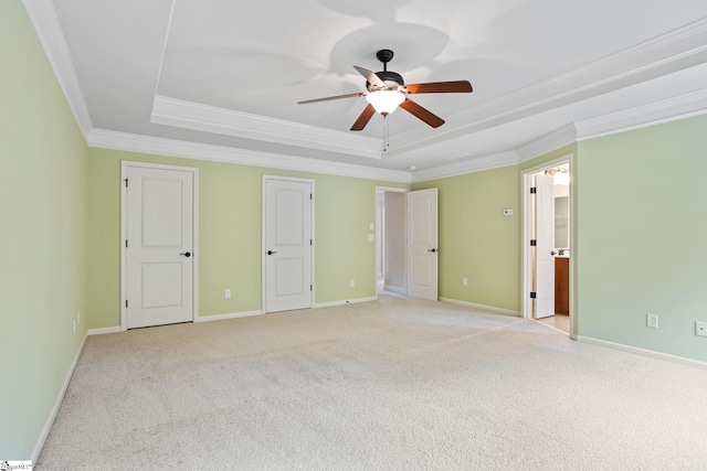 unfurnished bedroom with ceiling fan, light colored carpet, a tray ceiling, and ornamental molding