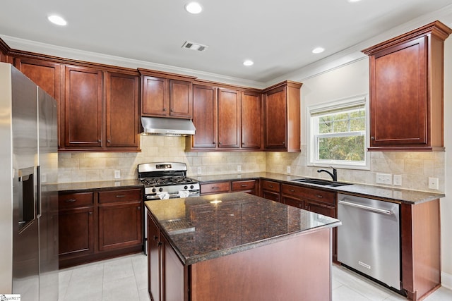 kitchen featuring appliances with stainless steel finishes, a center island, dark stone counters, sink, and crown molding