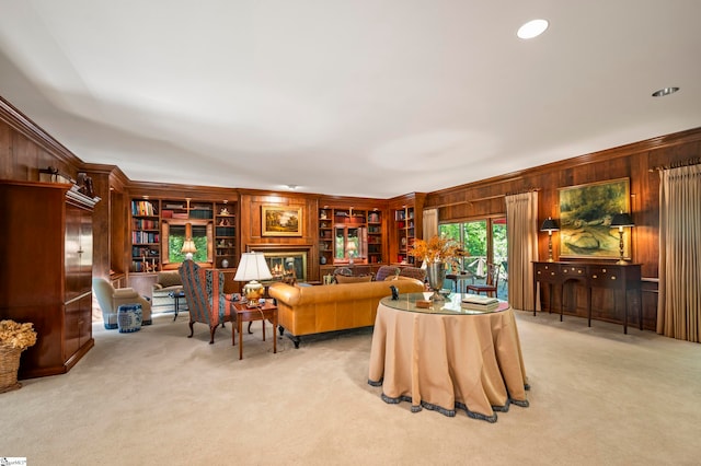 carpeted living room featuring ornamental molding, wooden walls, and built in features