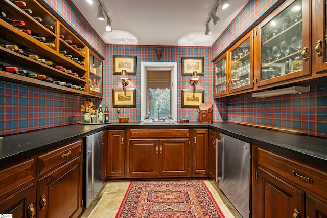 bar featuring stainless steel fridge, sink, and rail lighting