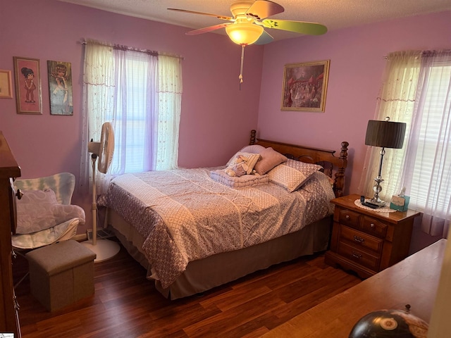 bedroom with ceiling fan, multiple windows, and dark hardwood / wood-style flooring