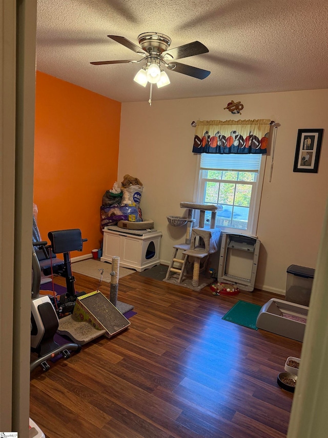 workout room featuring dark hardwood / wood-style floors, a textured ceiling, and ceiling fan