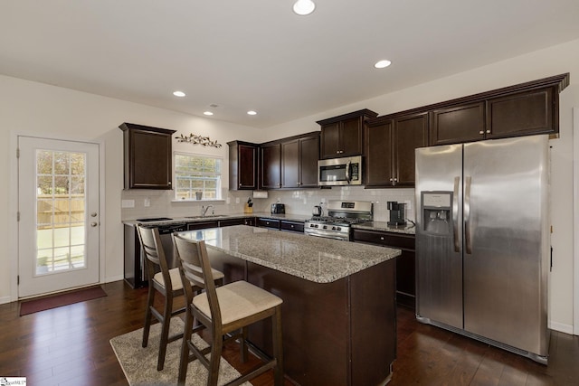 kitchen with a center island, appliances with stainless steel finishes, a healthy amount of sunlight, and dark hardwood / wood-style flooring