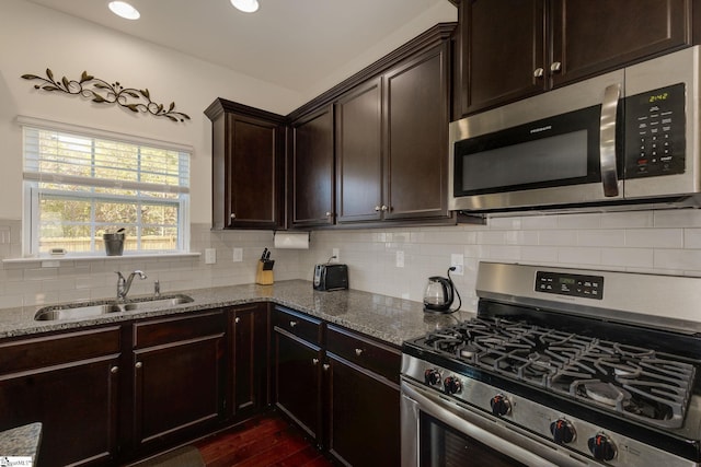 kitchen featuring decorative backsplash, dark hardwood / wood-style floors, stainless steel appliances, sink, and light stone counters