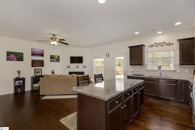 kitchen featuring decorative backsplash, a kitchen island, dark hardwood / wood-style flooring, dark brown cabinetry, and sink