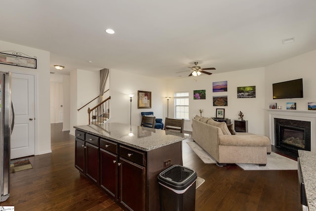 kitchen featuring dark wood-type flooring, a center island, light stone counters, and ceiling fan