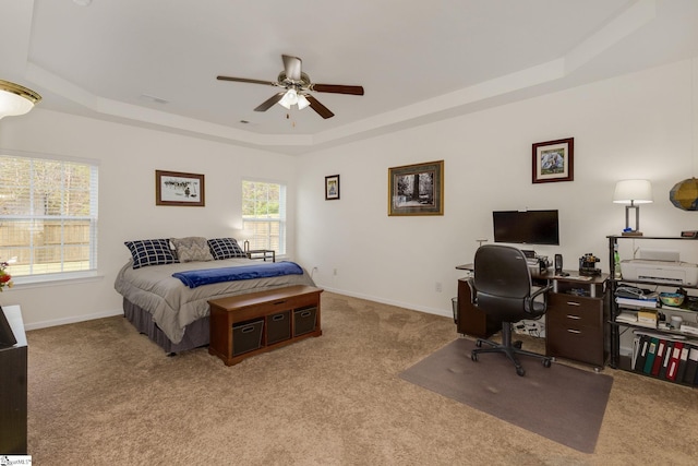 carpeted bedroom with ceiling fan and a raised ceiling