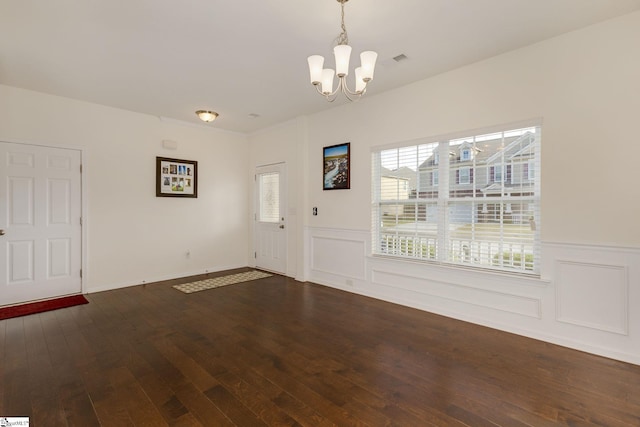 foyer entrance with dark wood-type flooring and a notable chandelier