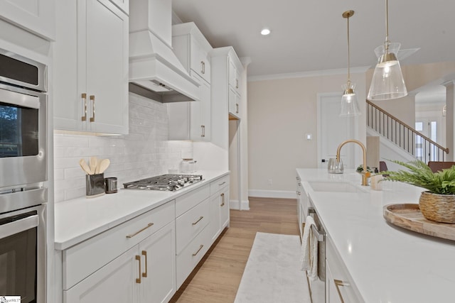 kitchen featuring premium range hood, stainless steel appliances, sink, decorative light fixtures, and white cabinets