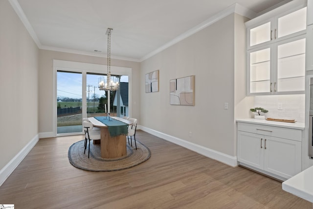 dining space featuring light hardwood / wood-style floors, crown molding, and a chandelier