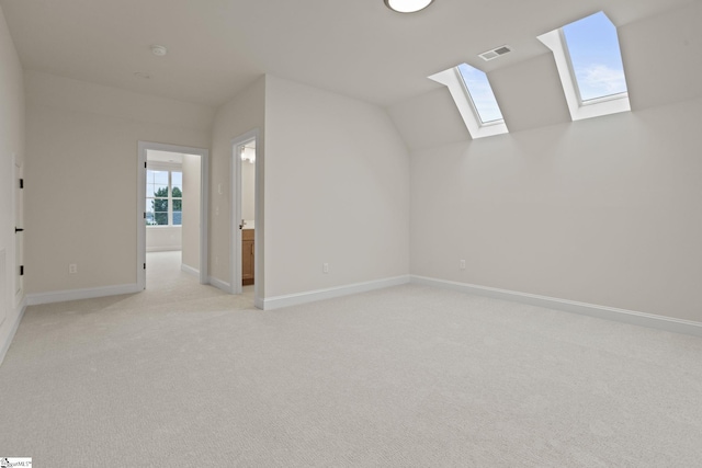 bonus room with lofted ceiling with skylight and light colored carpet