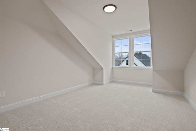 bonus room with light colored carpet and vaulted ceiling