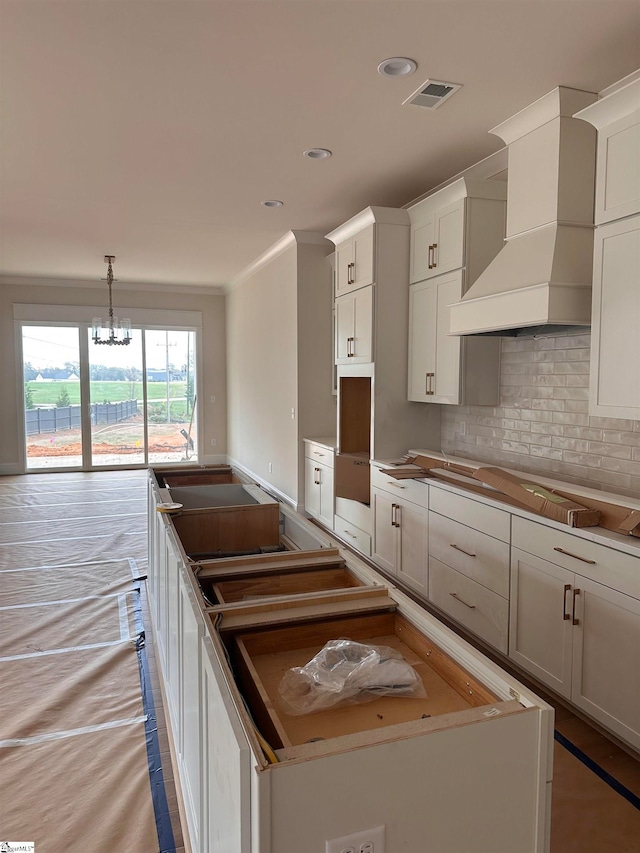 kitchen featuring a center island, premium range hood, white cabinetry, and tasteful backsplash