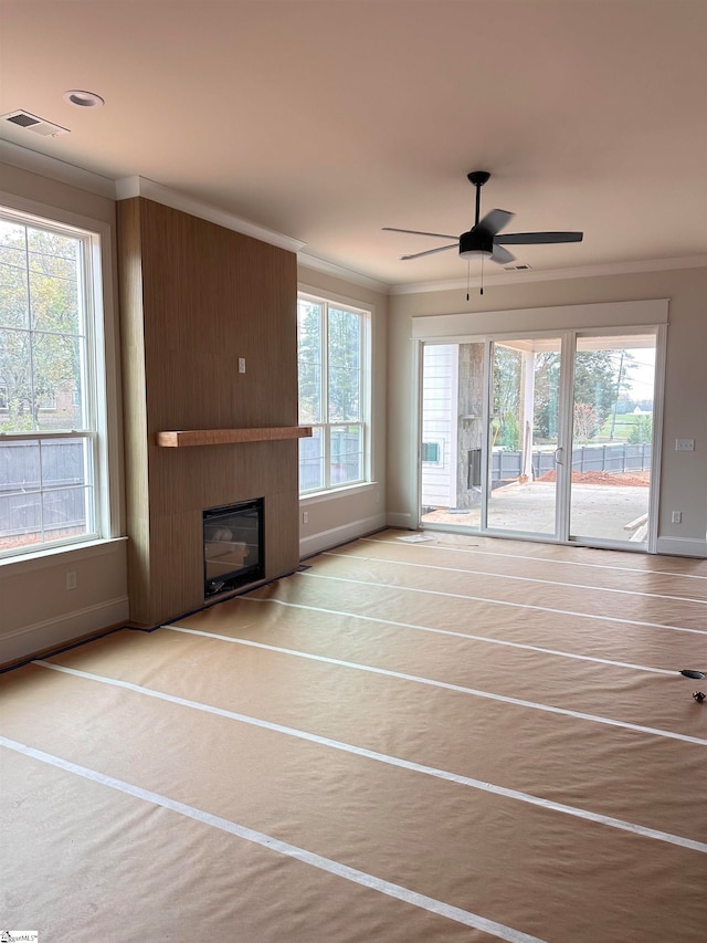 unfurnished living room with ceiling fan, a fireplace, and a healthy amount of sunlight