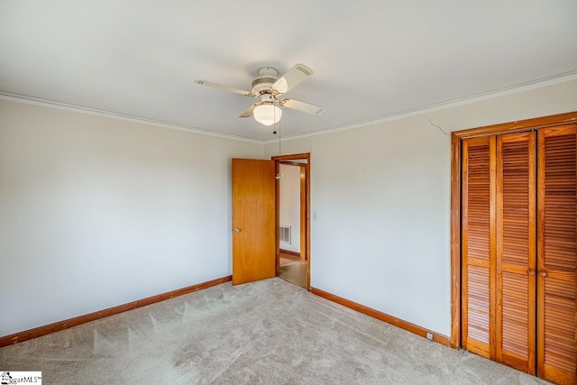 unfurnished bedroom with crown molding, a closet, light colored carpet, and ceiling fan