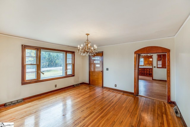 unfurnished room with crown molding, wood-type flooring, and an inviting chandelier