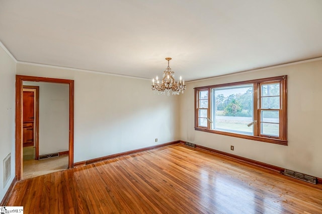 unfurnished room featuring crown molding, a notable chandelier, and light wood-type flooring