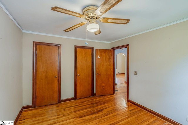 unfurnished bedroom with ornamental molding, light hardwood / wood-style flooring, two closets, and ceiling fan