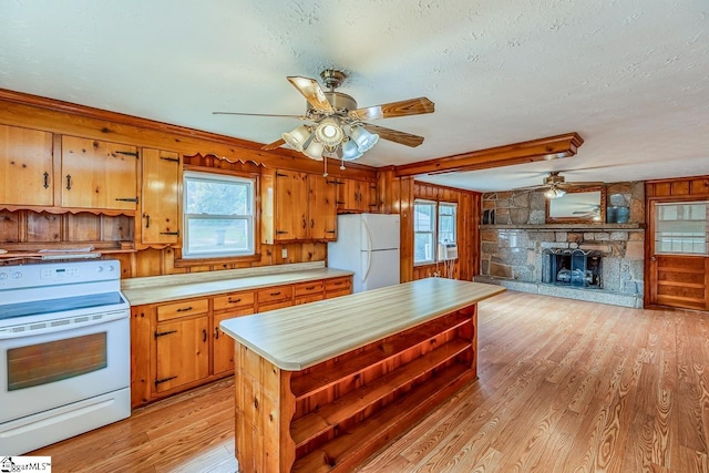 kitchen with light hardwood / wood-style flooring, a textured ceiling, wood walls, and white appliances