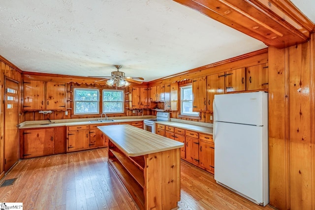 kitchen featuring white appliances, light hardwood / wood-style flooring, a wealth of natural light, and a center island