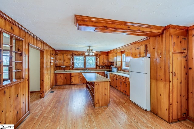 kitchen featuring white appliances, ornamental molding, light wood-type flooring, and a kitchen island