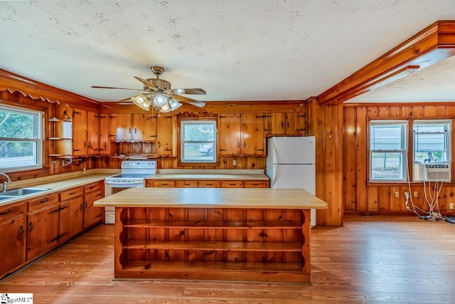 kitchen with sink, a kitchen island, white appliances, and light wood-type flooring